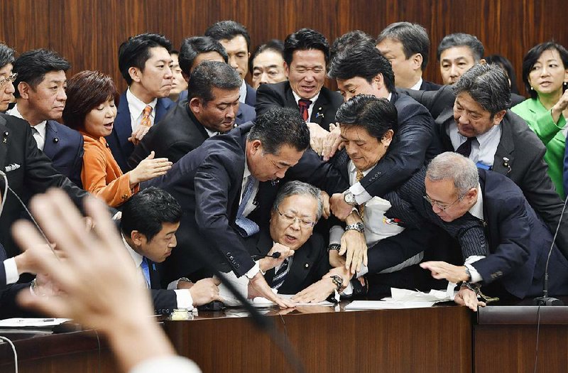 Members of Japan’s opposition parties try to prevent Shinichi Yokoyama, chairman of the legislature’s Judicial Affairs Committee, from moving to hold a vote on the foreign-labor bill Saturday in  Tokyo. 