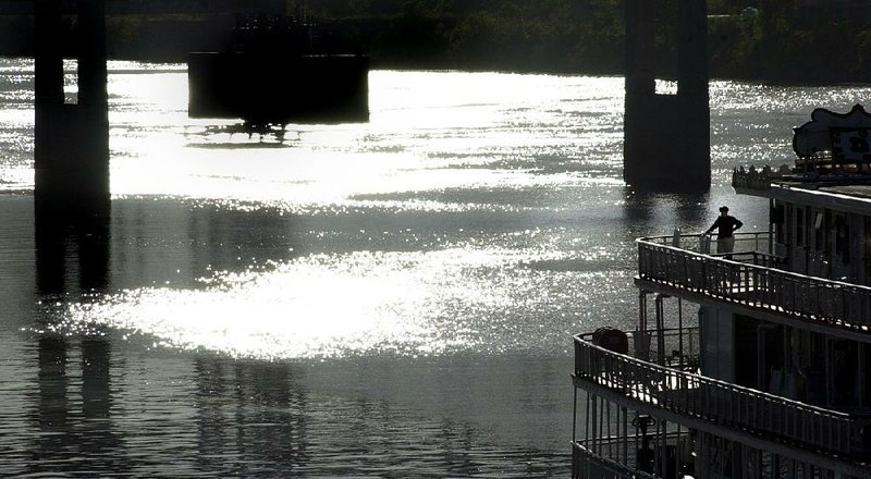 A passenger stands on the deck of the Delta Queen in 2001 as it sits at dock on the North Little Rock bank of the Arkansas River. The paddle-wheeler ceased overnight cruises in 2008 but could return to the water as early as 2020. 