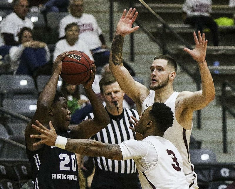 Central Arkansas guard Matthew Mondesir (left) looks to pass out of a double team set by UALR’s Rayjon Tucker (3) and Nikola Maric during the Bears’ 85-82 victory over the Trojans on Saturday at the Jack Stephens Center. 