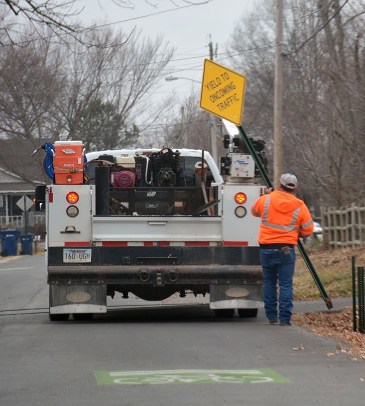 Hunter McFerrin/Siloam Sunday A city worker loads a yield sign into his truck on Thursday morning. The sign was part of the bike lane pilot project and was installed next to a "pinch point," that was on Harvard Street. The workers spent Thursday morning dismantling all but one of the pinch points, along with their signage, following a discussion on Tuesday night in which the city board voted to remove numerous components of the project.