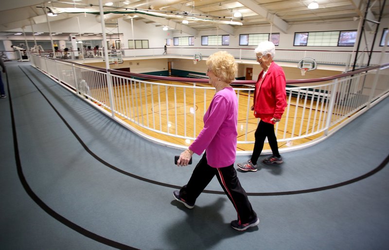 NWA Democrat-Gazette/DAVID GOTTSCHALK Carolyn Snow (left) and Joey Danenhauer walk Tuesday on the indoor track at Springdale's Recreation Center at Murphy Park. The city plans to sell the center to the Springdale School District and purchase the All-Star Sports Arena in Springdale.