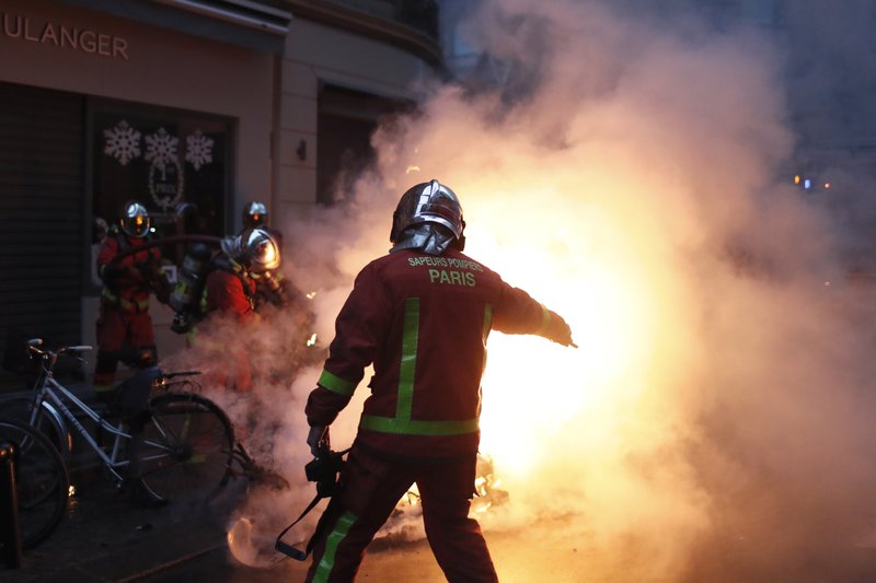 Firefighters try to extinguished a car set on fire by demonstrators during clashes with riot police, in Paris, France, Saturday, Dec. 8, 2018. Crowds of protesters angry at President Emmanuel Macron and France's high taxes tried to converge on the presidential palace Saturday, some scuffling with police firing tear gas, amid exceptional security measures aimed at preventing a repeat of last week's rioting. (AP Photo/Thibault Camus)
