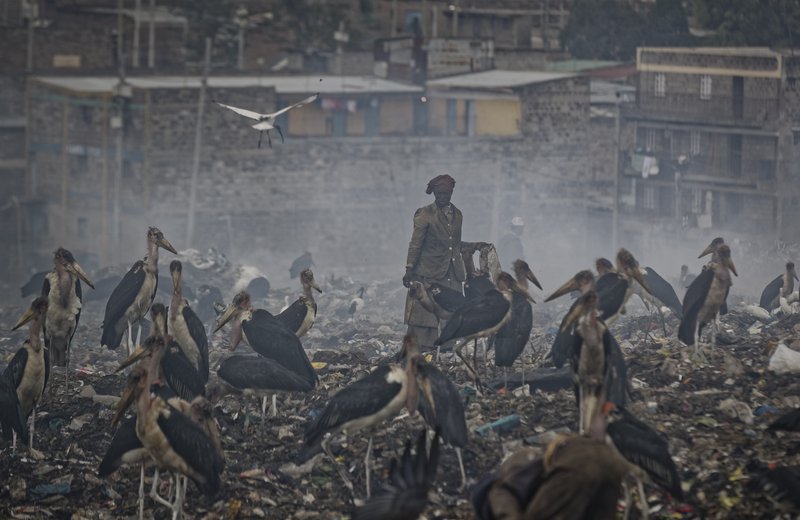 The Associated Press SOLID WASTE: A woman who scavenges recyclable materials from garbage for a living is seen through a cloud of smoke from burning trash Wednesday, surrounded by Marabou storks who feed on the garbage, at the dump in the Dandora slum of Nairobi, Kenya. As the world meets again to tackle the growing threat of climate change, how the continent tackles the growing solid waste produced by its more than 1.2 billion residents, many of them eager consumers in growing economies, is a major question in the fight against climate change.