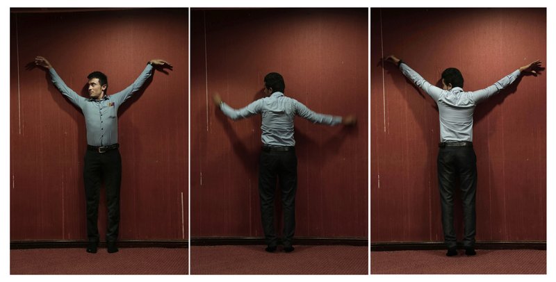 Yemeni medic Farouk Baakar demonstrates how he was shackled to a wall during his torture in a prison run by Yemen's Houthi rebels, in this combination of three photos taken on July 29, 2018 in Marib, Yemen. Baakar was one of thousands of people who have been imprisoned by Houthi militia during four years of civil war. Many of them, an Associated Press investigation has found, have suffered extreme forms of torture _ smashed in their faces with batons, hung from chains by their wrists or genitals for weeks at time, scorched with acid or fingers torn from their hands. (AP Photo/Nariman El-Mofty)