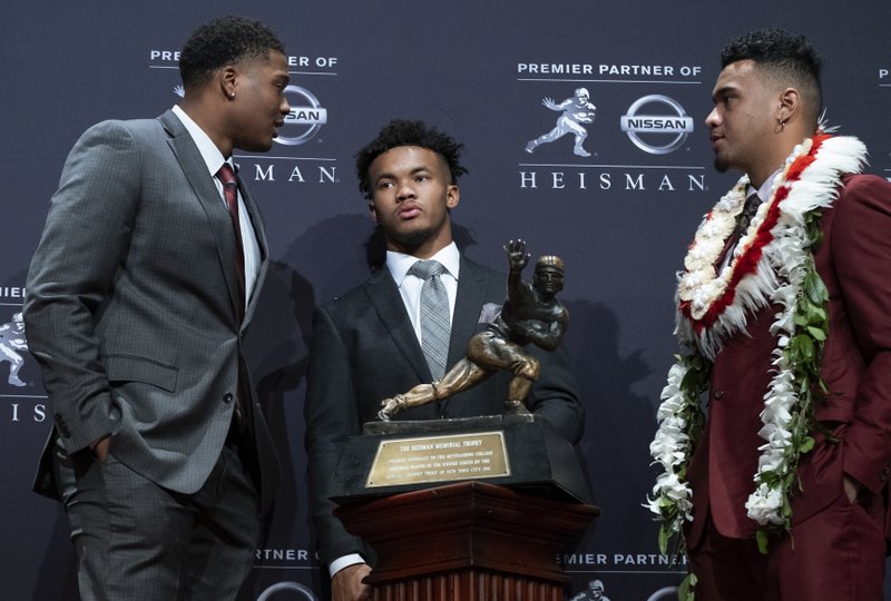 Heisman Trophy finalists, from left, Dwayne Haskins, from Ohio State; Kyler Murray, from Oklahoma; and Tua Tagovailoa, from Alabama, stand near the trophy during a media event Saturday, Dec. 8, 2018, in New York. (AP Photo/Craig Ruttle)