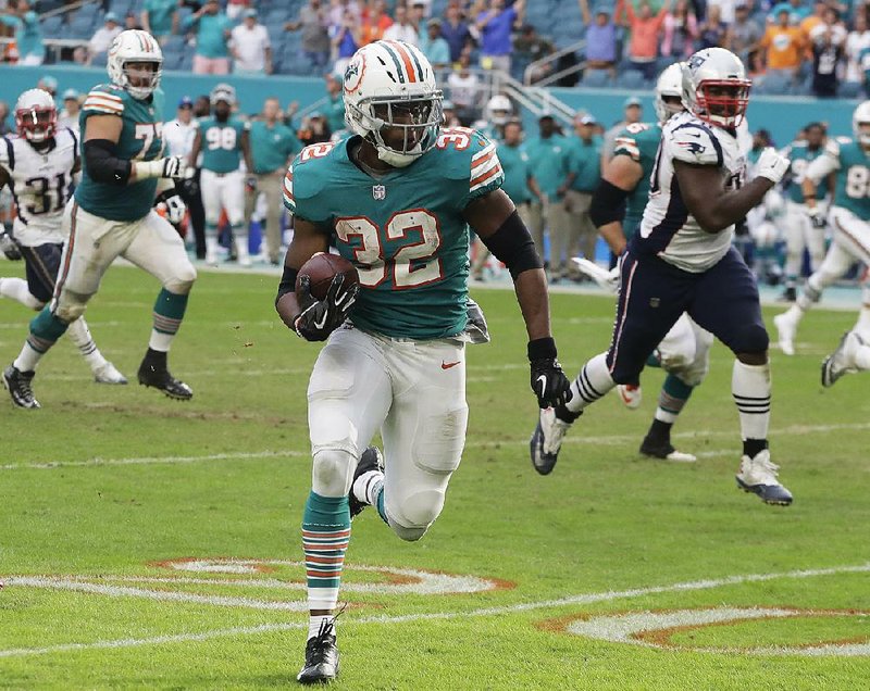 Kenyan Drake runs the last 52 yards as the Miami Dolphins scored on a pass and double lateral on the final play Sunday to beat the New England Patriots 34-33 in Miami Gar- dens, Fla.