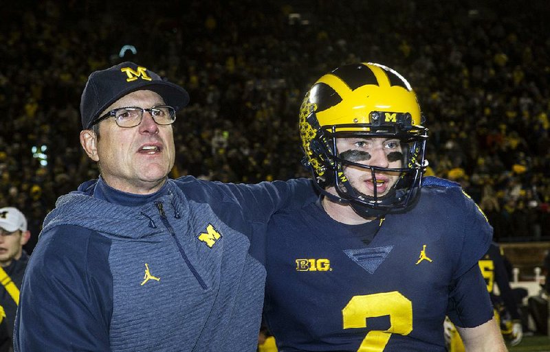 Michigan head coach Jim Harbaugh, left, puts an arm around Michigan quarterback Shea Patterson after defeating Indiana 31-20 in an NCAA college football game, in Ann Arbor, Mich. No. 4 Michigan is in a position to win a Big Ten title for the first time since 2004 in part because the NCAA allowed Ole Miss transfer Shea Patterson to play this season for Jim Harbaugh.