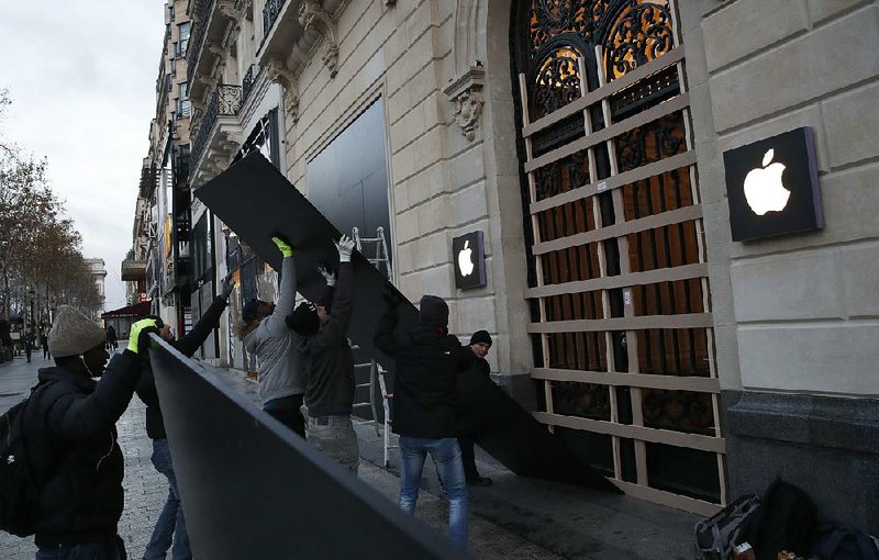 Workers remove wooden planks from shop windows on the Champs-Elysees avenue in Paris on Sunday as stores reopened after Saturday’s protests.