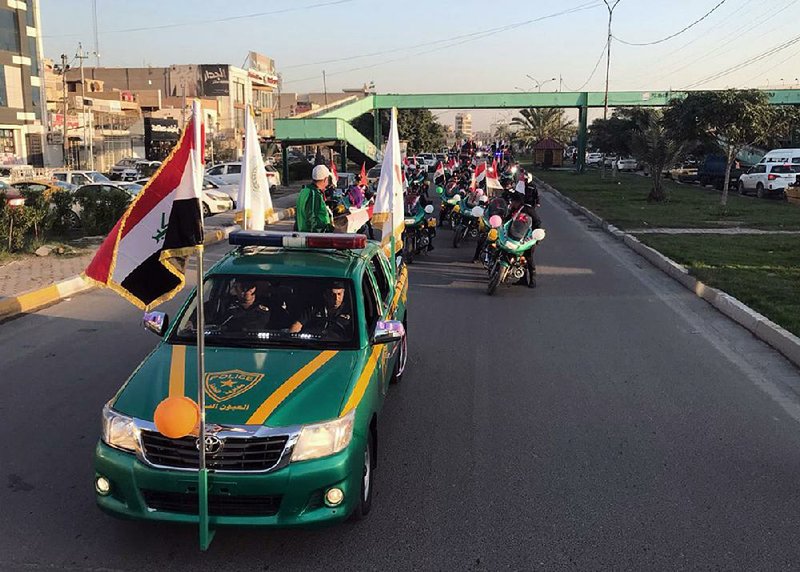 Iraqi security forces raise Iraqi national flags in a parade marking the anniversary of the defeat of the Islamic State group in Iraq in Tahrir Square, Baghdad, on Monday.