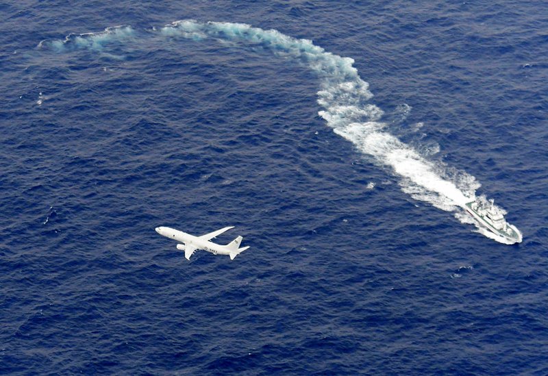 FILE - In this Dec. 6, 2018, file photo, Japan's Coast Guard ship, top, and U.S. military plane are seen at sea off Kochi, southwestern Japan, during a search and rescue operation for missing crew members of a U.S. Marine refueling plane and fighter jet. The U.S. Marine Corps have declared that five crewmembers dead after their aircraft crashed last week off Japan's southern coast and that their search has ended. (Kyodo News via AP, File)