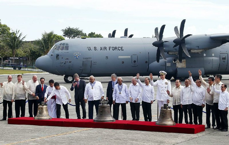 U.S. and Philippines officials stand with the bells of Balangiga after their delivery by an Air Force C-130 Tuesday in a televised ceremony at an airport on the outskirts of Manila. 