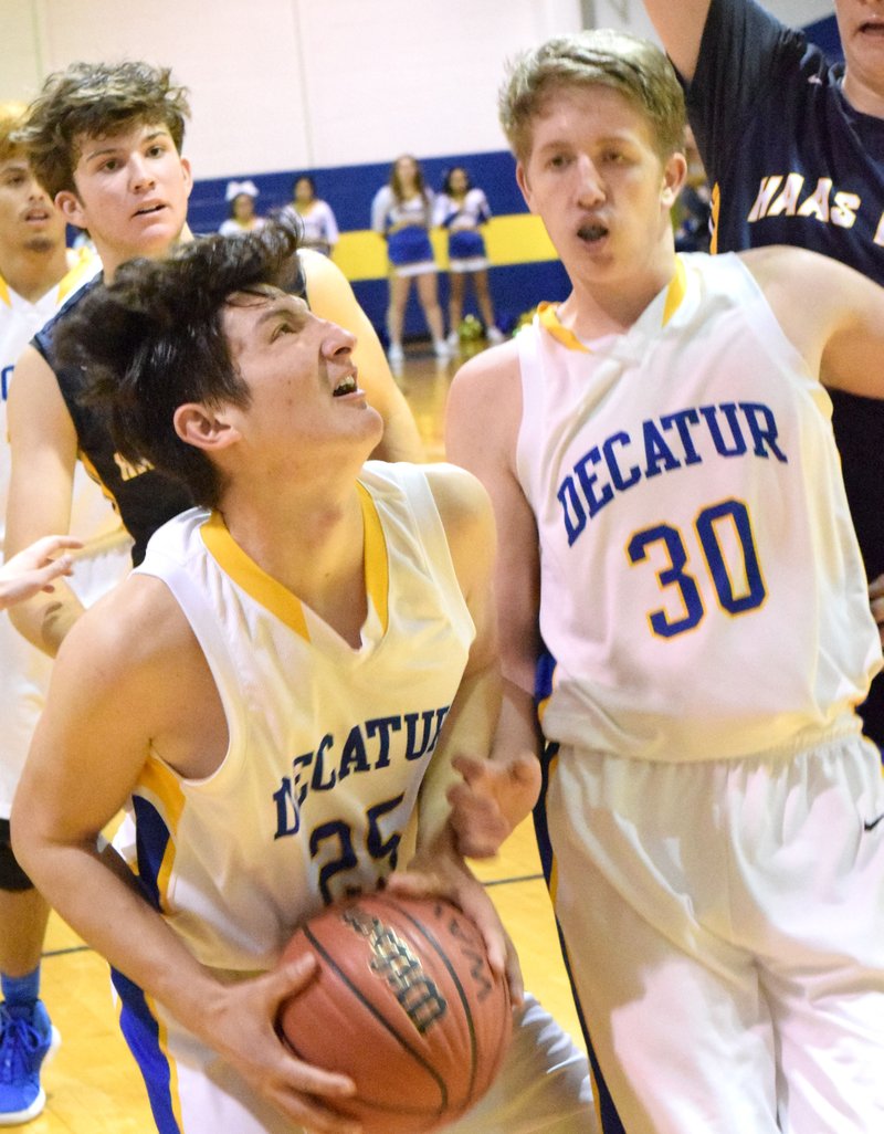 Westside Eagle Observer/MIKE ECKELS After pulling down a rebound, Kevin Garcia (Decatur 25) fights to put up a layup as his teammate Ryan Ross (30) tries to back out of his way during the Decatur-Haas Hall conference basketball game in Decatur Dec. 4.