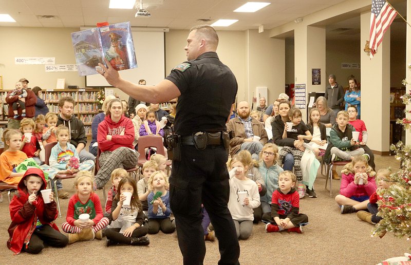 LYNN KUTTER/ENTERPRISE-LEADER Bo Mitchell, school resource officer with Prairie Grove Police Department, reads the book, "Cop's Night Before Christmas," at the Family Holiday Night for Prairie Grove Elementary School on Dec. 6. School Resource Officer David Faulk read earlier, "Cajun Night Before Christmas," and both officers drew the attention of lots of children. About 500 attended the annual family evening.