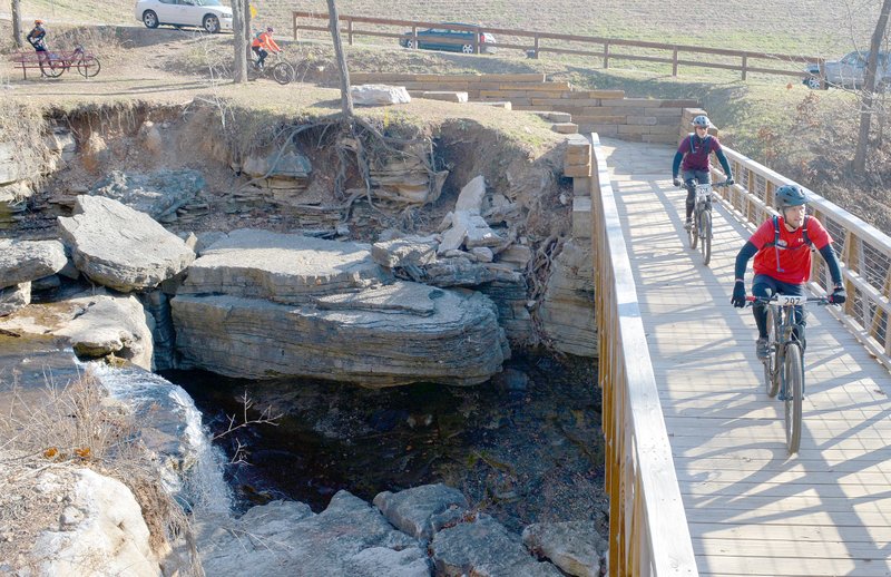 Keith Bryant/The Weekly Vista A pair of riders cross the Lake Ann spillway while others stop at a nearby aid station.