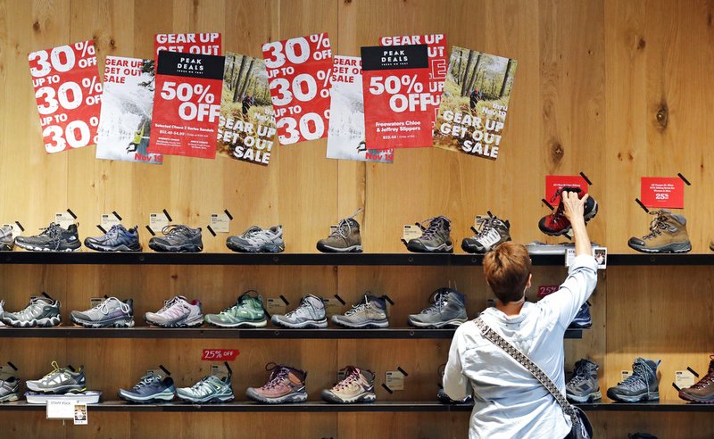 FILE - In this Nov. 13, 2018, file photo, a shopper looks at hiking boots during a sale in REI Co-op's flagship store in Seattle. U.S. consumer prices were unchanged in November, the best performance since prices actually fell eight months ago. (AP Photo/Elaine Thompson, File)