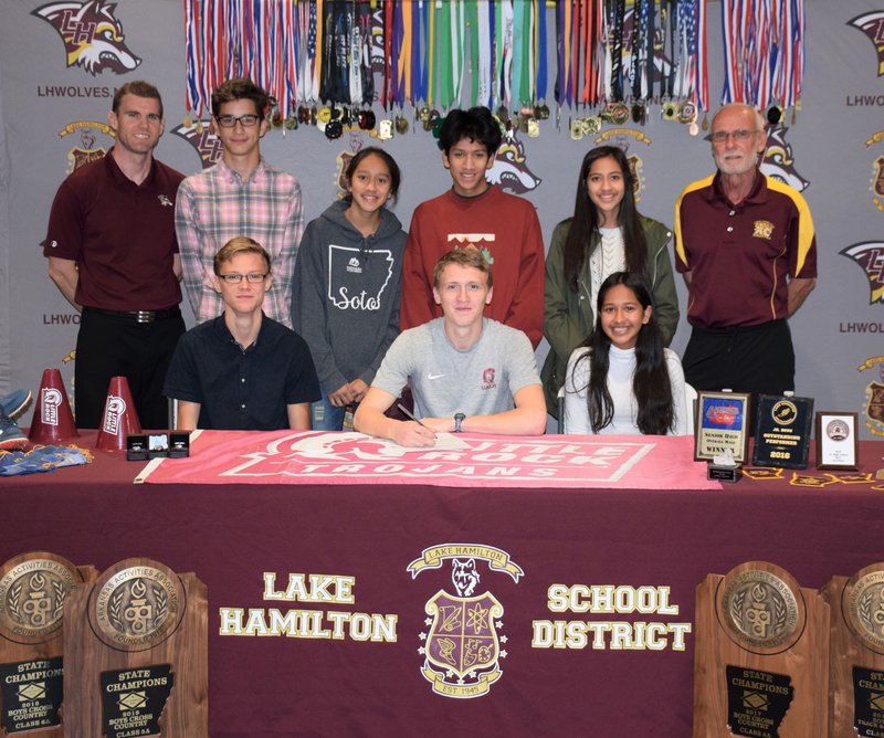 Submitted photo FUTURE UALR TROJAN: Lake Hamilton senior Colby Swecker, seated center, was joined by a number of supporters on Wednesday at Wolf Arena when he signed to run cross country and track and field in college for the Little Rock Trojans. Among those present, in front, were William Swecker, left, and Anacaren Ramos, right; and back, Lake Hamilton assistant coach Brandon Smith, left; Skylar Davis, second from left; and Lake Hamilton head coach Karl Koonce, right.