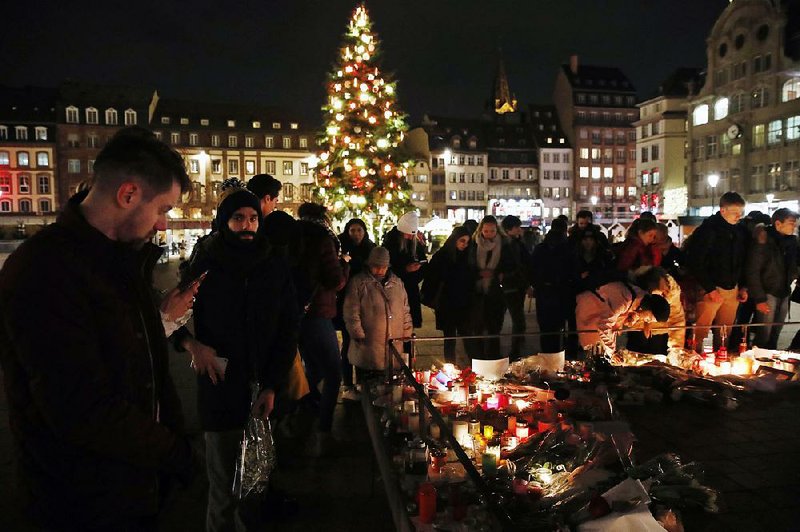 People pay their respects Thursday to the victims of Tuesday’s fatal shooting in a Christmas market in Strasbourg, France. 