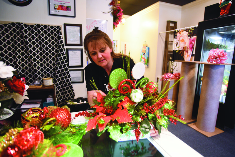 Bridget Joslin, co-owner of Bridget’s On The Square, proofs a Christmas arrangement at her downtown Magnolia floral shop.