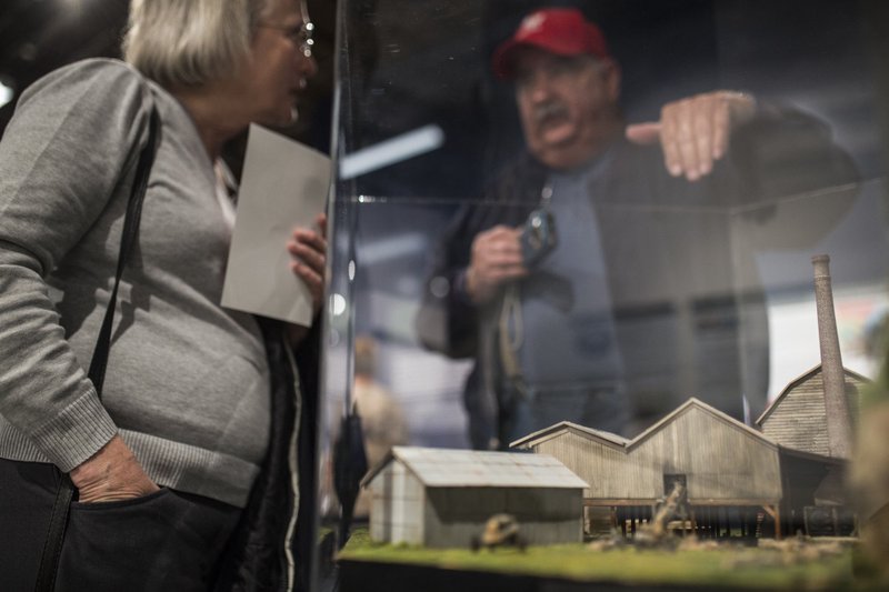 NWA Democrat-Gazette/CHARLIE KAIJO Sam Syzdek (right) talks Thursday to Allyn Lord, director of the Shiloh Museum, about a Van Winkle Mill replica he built during an opening at the Rogers Historical Museum. The museum had an opening after moving to the former Hailey Ford/Rogers Morning News building.