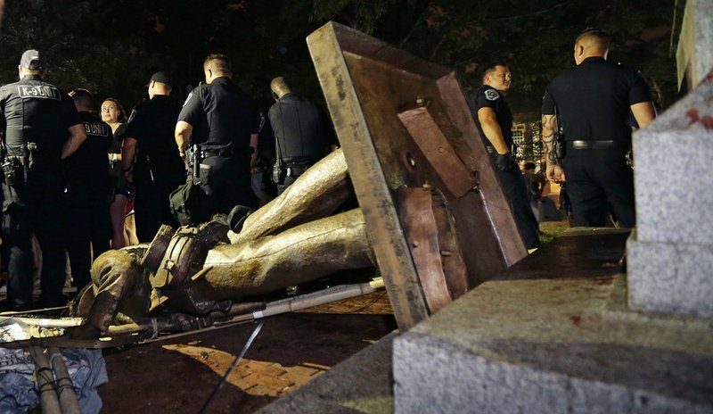 In this Monday, Aug. 20, 2018, file photo, police stand guard after the Confederate statue known as Silent Sam was toppled by protesters on campus at the University of North Carolina in Chapel Hill, N.C. The board overseeing North Carolina's public universities is meeting to decide the fate of "Silent Sam." The University of North Carolina System Board of Governors was meeting Friday, Dec. 14, to discuss a proposal to build a $5 million building to house the statue at UNC-Chapel Hill. (AP Photo/Gerry Broome, File)