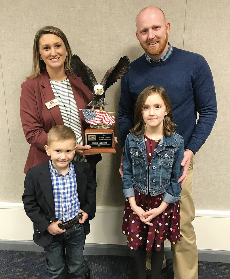 Dana Stewart, top left, holds the Stanley E. Reed Leadership Award, that she received from the Arkansas Farm Bureau during its annual conference Nov. 28 at the Hot Springs Convention Center. She is pictured with her husband, Joshua, and children, Henry, left, and Jewel