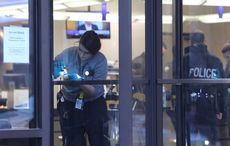 A Little Rock police crime scene technician processes fingerprints after a robbery at the Arvest Bank in downtown Little Rock on Friday.