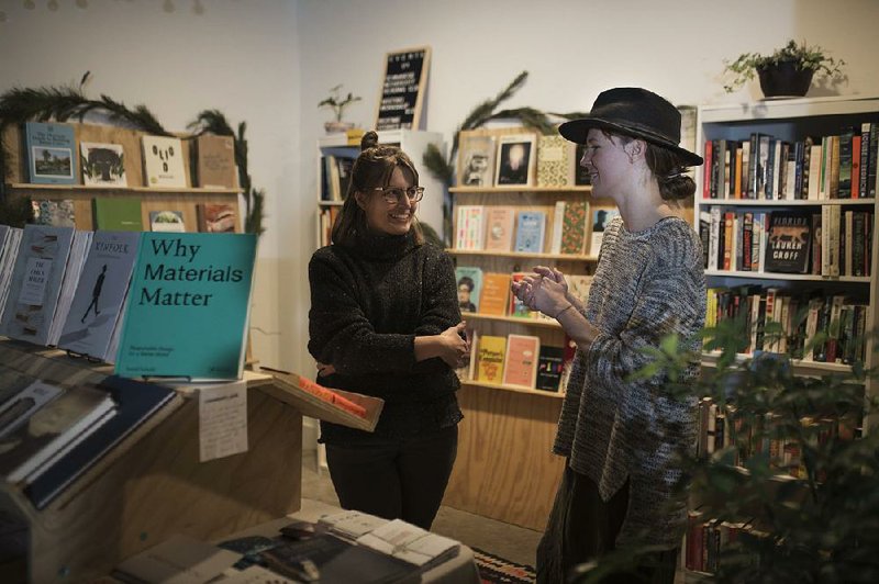 Co-owners Monica Diodati (left) and Rachel Slaton talk at their pop-up shop Two Friends Books and Records in Airship Coffee in Bentonville. 