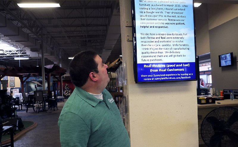Brad Schweig, co-owner of Sunnyland Furniture, looks at a video screen displaying a review of his business in Dallas. 