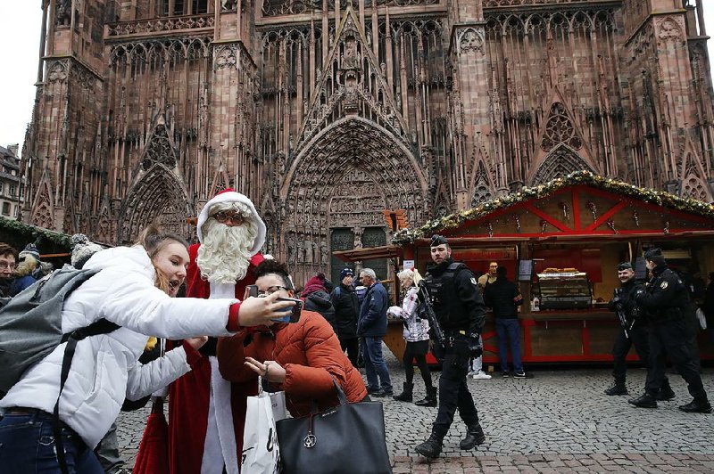 Tourists in Strasbourg, France, get a photo with Santa at the Christmas market, which reopened Friday with a heavy police presence after it was closed for two days. 