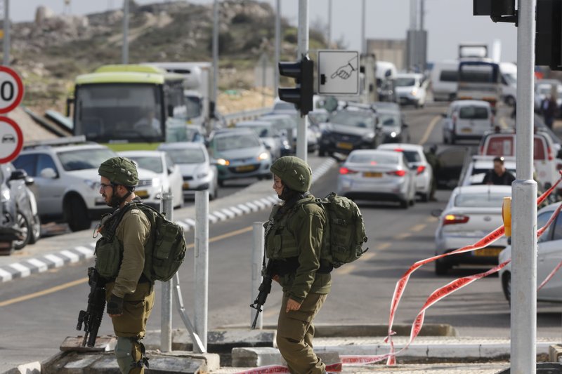 Israeli soldiers stand at the scene of an attack near the settlement of Givat Assaf in the West Bank, Thursday, Dec. 13, 2018. A Palestinian gunman opened fire at a bus stop outside a West Bank settlement on Thursday, shooting at soldiers and civilians and killing at least two Israelis before fleeing, the military and Israel's rescue service said. (AP Photo/Nasser Shiyoukhi)