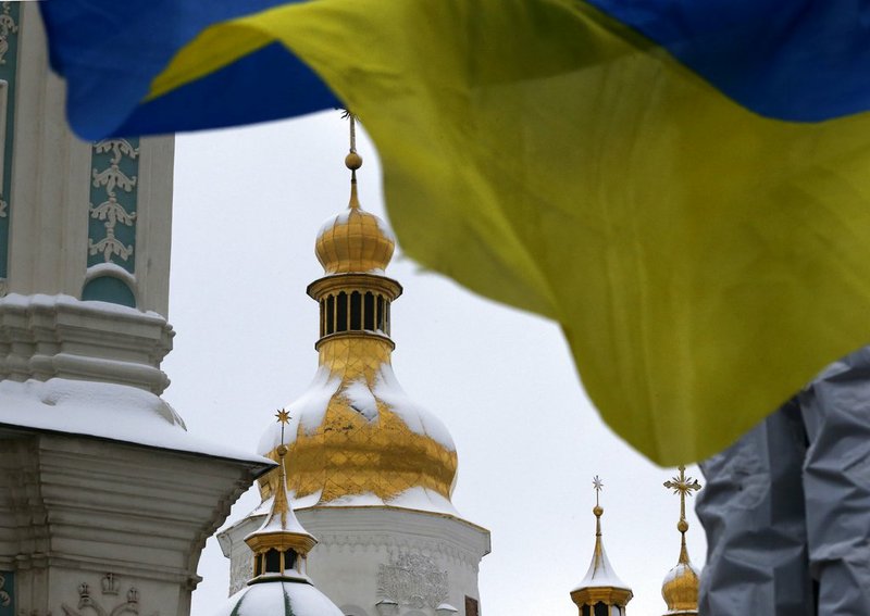A Ukrainian national flag flutters in the wind as people gather to support independent Ukrainian church near the St. Sophia Cathedral in Kiev, Ukraine, Saturday, Dec. 15, 2018. Ukraine's Orthodox clerics gather for a meeting Saturday that is expected to form a new, independent Ukrainian church, and Ukrainian authorities have ramped up pressure on priests to support the move. (AP Photo/Efrem Lukatsky)