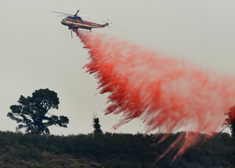 FILE - In this Aug. 13, 2016 file photo, a fire attack helicopter makes a retardant drop during a firing operation on the ridge between Mount Manuel and the Coast Ridge Road while fighting the Soberanes Fire near the village of Big Sur, Calif. The so-called Soberanes Fire burned its way into the record books as the most expensive wildland firefight in U.S. history in what a new report calls "an extreme example of excessive, unaccountable, budget-busting suppression spending that is causing a fiscal crisis in the U.S. Forest Service." (David Royal/The Monterey County Herald via AP, File)