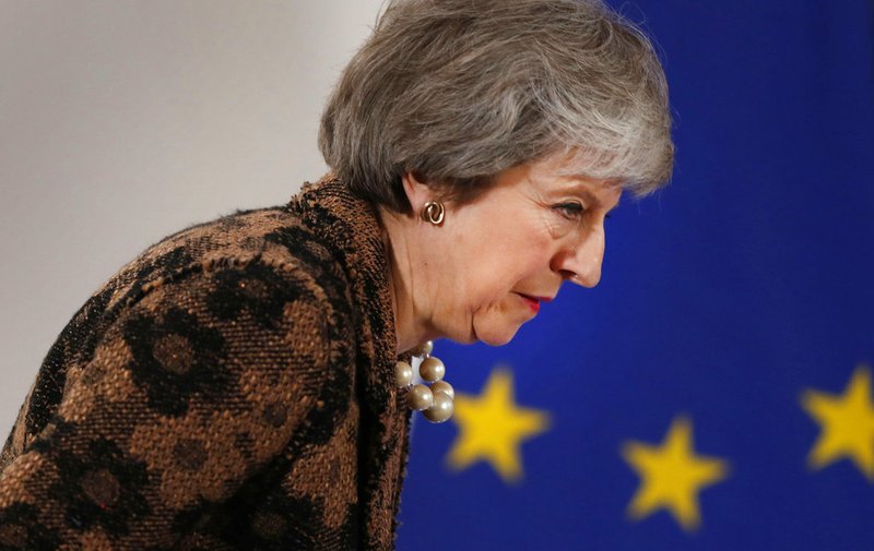 British Prime Minister Theresa May walks by the EU stars as she arrives for a media conference at an EU summit in Brussels, Friday, Dec. 14, 2018. European Union leaders expressed deep doubts Friday that British Prime Minister Theresa May can live up to her side of their Brexit agreement and they vowed to step up preparations for a potentially-catastrophic no-deal scenario. (AP Photo/Alastair Grant)