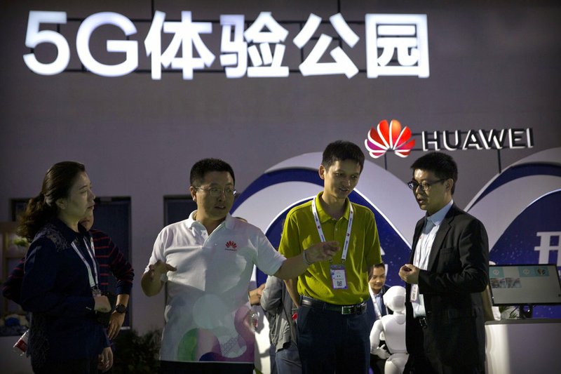 FILE - In this Sept. 26, 2018, file photo, visitors look at a display for 5G wireless technology from Chinese technology firm Huawei at the PT Expo in Beijing. While a Huawei executive faces possible U.S. charges over trade with Iran, the Chinese tech giant's ambition to be a leader in next-generation telecoms is colliding with security worries abroad. (AP Photo/Mark Schiefelbein, File)