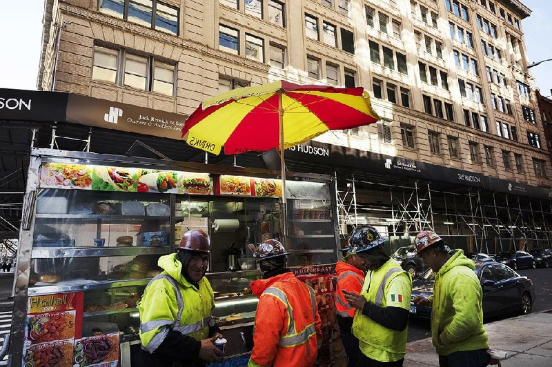 Construction workers buy food from a street cart Monday in front of a building that has been chosen by Google as part of its expansion plans in New York. 