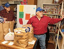 The Sentinel-Record/Richard Rasmussen COMMUNITY SUPPORT: Frank Rysan, left, and Frank Mantell, both of Hot Springs Village, package food bags at Jackson House Monday. Executive Director Janie Smith said Monday the organization needs the community's support, especially during the holidays.