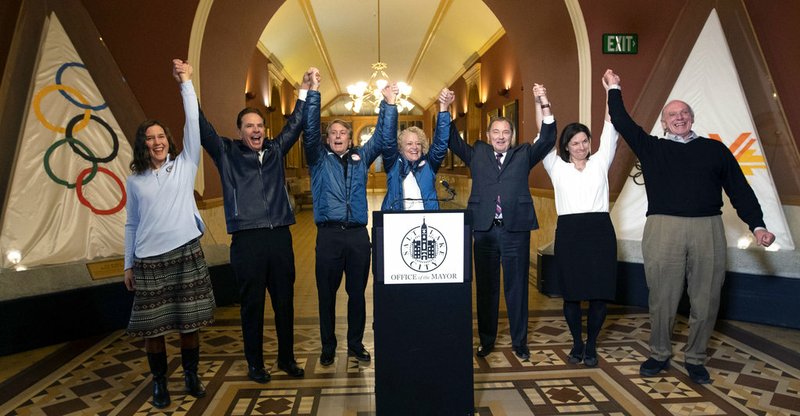 Salt Lake City Council Chairwoman Erin Mendenhall, Fraser Bullock, chief operating officer of the 2002 Winter Games, Jeff Robbins, president and CEO of the Utah Sports Commission, Salt Lake City Mayor Jackie Biskupski, Gov. Gary Herbert, USA Olympic speed skater Catherine Rainey-Norman and Salt Lake County Councilman Jim Bradley raise their arms in celebration after the USOC choose Salt Lake over Denver to bid on behalf of the U.S. for future Winter Games, Friday, Dec. 14, 2018 in Salt Lake City. Salt Lake City got the green light to bid for the Winter Olympics -- most likely for 2030 -- in an attempt to bring the Games back to the city that hosted in 2002 and provided the backdrop for the U.S. winter team's ascendance into an international powerhouse. (Steve Griffin/The Deseret News via AP)
