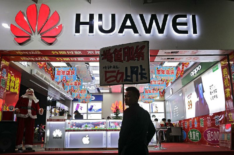 A worker holds a sign promoting Huawei 5G Internet services Tuesday at a mobile phone shop in Shenzhen,China.