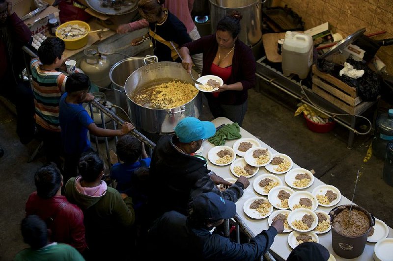 Honduran migrants get breakfast Tuesday in a warehouse in downtown Tijuana, Mexico. The United States will contribute $10.6 billion to an assistance program to curb Central American migration. 