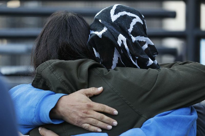 A Honduran asylum seeker, his face covered by a blanket, embraces an immigration activist Tuesday in Tijuana, Mexico, before entering the Otay Mesa border crossing in San Diego. 