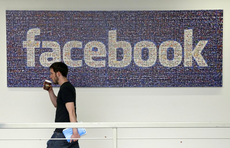 FILE - In this March 15, 2013, file photo, a man walks past a sign at Facebook headquarters in Menlo Park, California, USA. Facebook gave some companies more extensive access to users' personal data than it has previously revealed, letting them read private messages or see the names of friends without consent, according to a New York Times report published Wednesday Dec. 19, 2018. (AP Photo/Jeff Chiu, File)
