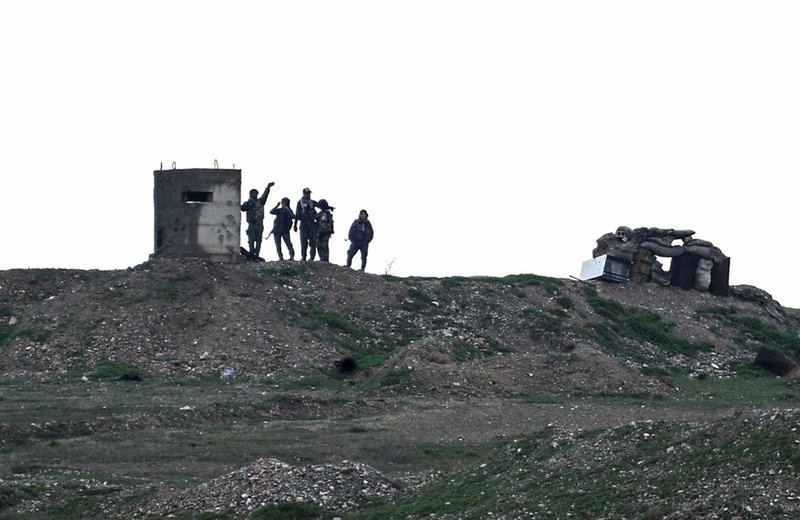 Fighters of People's Protection Units, or YPG, gather at their outpost west of the city of Kobani, northern Syria, Tuesday, Dec. 18, 2018. Turkey has vowed to launch a new offensive against YPG, which is the main component of a U.S.-allied force that drove Islamic State militants out of much of eastern Syria. U.S. troops are based in the area, in part to reduce tensions. (Ugur Can/DHA via AP)