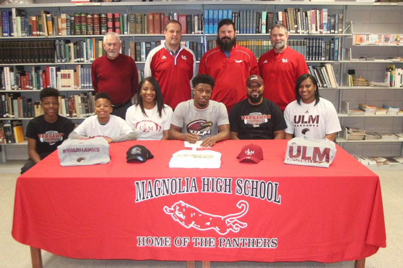 Magnolia running back Kadyn Roach is all smiles after signing his NCAA Division I letter-of-intent Wednesday morning with the University of Louisiana-Monroe Warhawks. Joining him in the signing were (seated from left) brothers Amare and Kaleb Roach, mother Audrea Roach, parents Kerry and Sharonda Roach. Standing (from left) are Magnolia Athletic Director Marvin Lindsey Jr., head football coach John Panter, offensive coordinator Trey Lavalle and defensive coordinator Ernest Pressley.