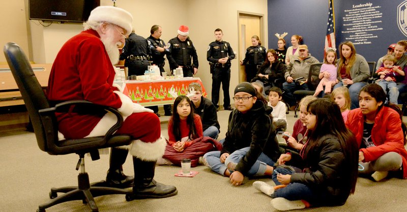 Hunter McFerrin/Siloam Sunday The Siloam Springs Police Department held its annual "Shop with a Cop" event on Thursday night, where a group of kids in the community were able to go on a shopping trip with officers. The event began at the police department, where milk and cookies were served to the kids and their parents, following a visit from Santa. Afterwards, everyone made their way to the Walmart Supercenter on U.S. Highway 412. Above, a girl waits as Santa begins to answer her question.