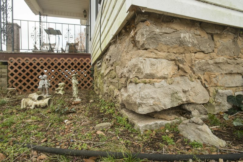 NWA Democrat-Gazette/BEN GOFF &#8226; @NWABENGOFF Stones and mortar crumble from the foundation Wednesday at the Rogers Cemetery manager's house on South 10th Street in Rogers. The cemetery manager is required to live in the aging house as part of the job description.