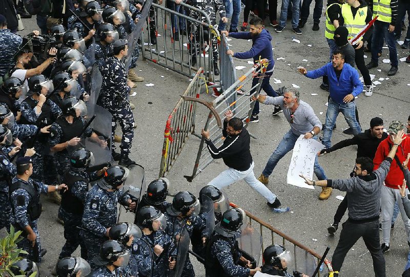 A Lebanese protester shouts at riot police Sunday outside the government headquarters in Beirut. 