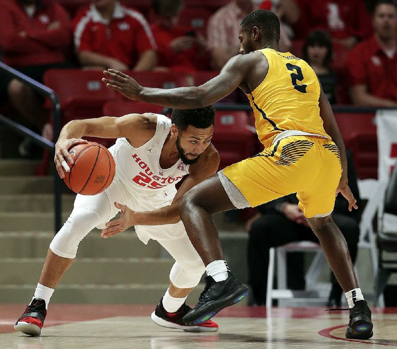 Houston guard Galen Robinson Jr. (25) looks to drive around Coppin State guard Taqwain Drummond (2) in the Cougars’ 75-44 victory Sunday.