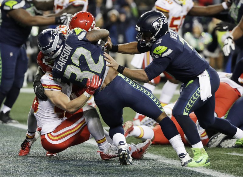 Seattle Seahawks running back Chris Carson (32) scores a touchdown against the Kansas City Chiefs as quarterback Russell Wilson, right, pushes during the second half of an NFL football game, Sunday, Dec. 23, 2018, in Seattle. (AP Photo/Elaine Thompson)