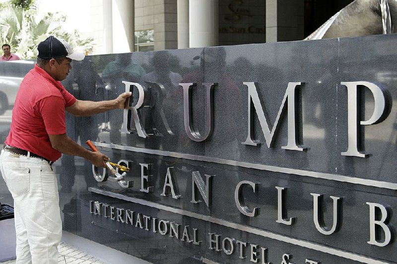 A worker removes the word Trump from a marquee outside the Trump Ocean Club International Hotel and Tower in Panama City, Panama, in March. Many believed the presidency would be a boon to Donald Trump’s businesses, but two years since he took office signs are mounting that it has had the opposite effect. 