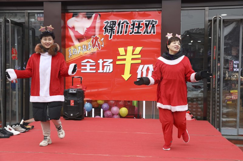 In this photo Saturday, Dec. 22, 2018, photo, sales staff from an apparel shop dance wearing Christmas themed costumes to promote a year end sales in Zhangjiakou in northern China's Hebei province. At least four Chinese cities and one county have restricted Christmas celebrations this year. Churches in another city have been warned to keep minors away from Christmas, and at least ten schools nationwide have curtailed Christmas on campus, The Associated Press has found. (AP Photo/Ng Han Guan)